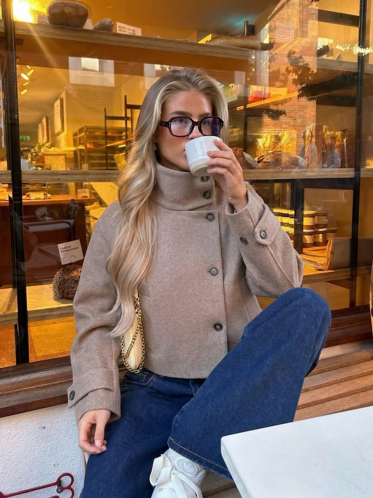 Graue Kurzjacke zu Jeans vor einem Schaufenster, Streetstyle-Aufnahme
