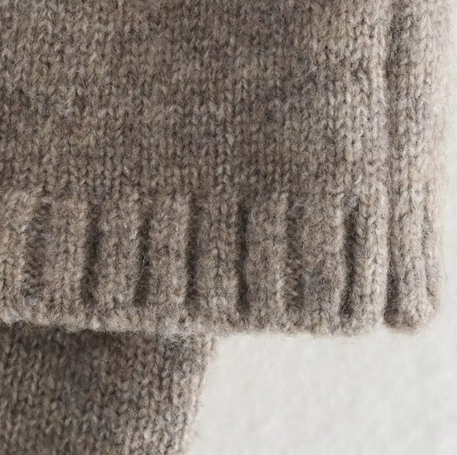 Detailaufnahme der Rippstruktur am Saum des grauen Strickcapes