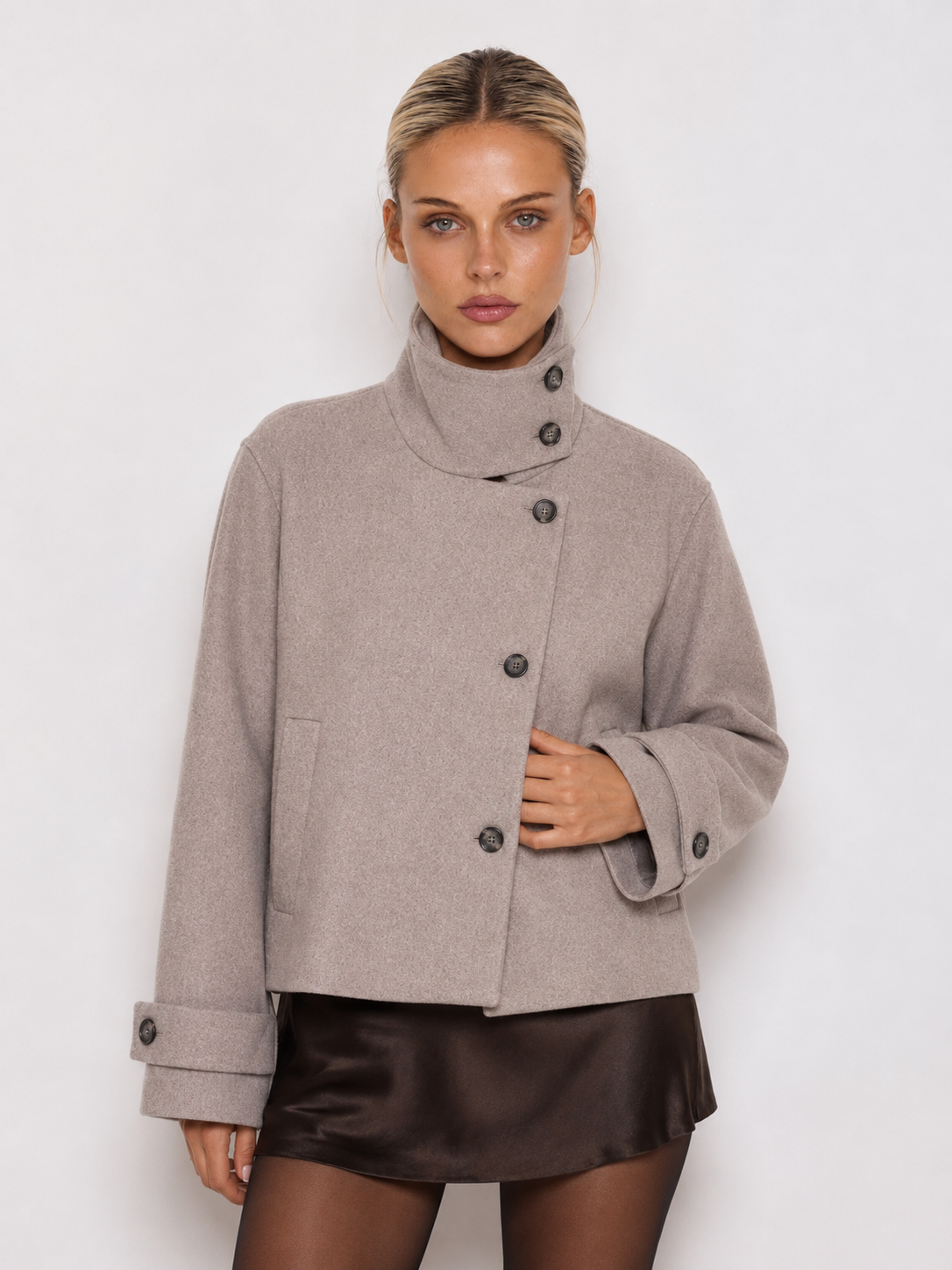 Model in kurzer grauer Jacke, die Hand richtet die Manschette mit Knopfriegel