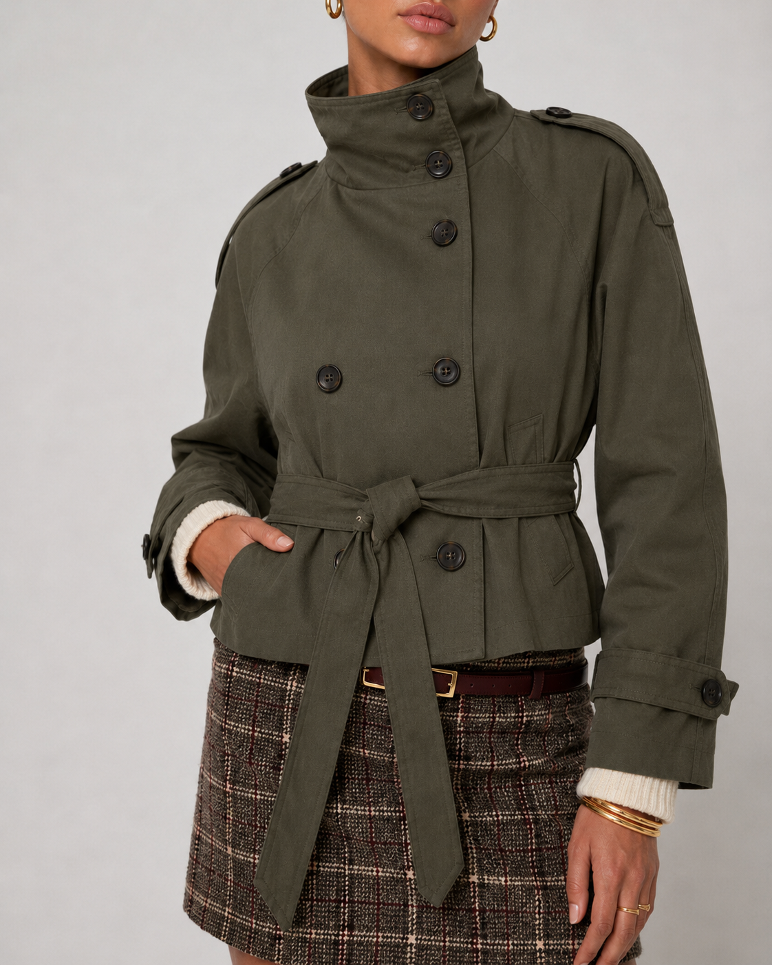 Kurzer Trenchcoat in Armygrün von der Seite, mit betonten Schultern und Ärmelriegeln